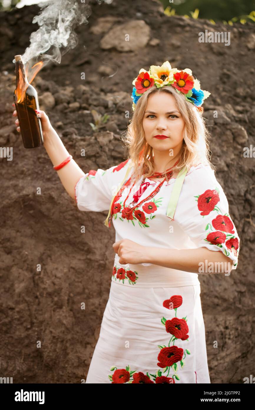 Una ragazza in un abito ricamato nazionale ucraino con un cocktail Molotov nelle sue mani, un simbolo dell'Ucraina che si difende contro gli invasi russi Foto Stock
