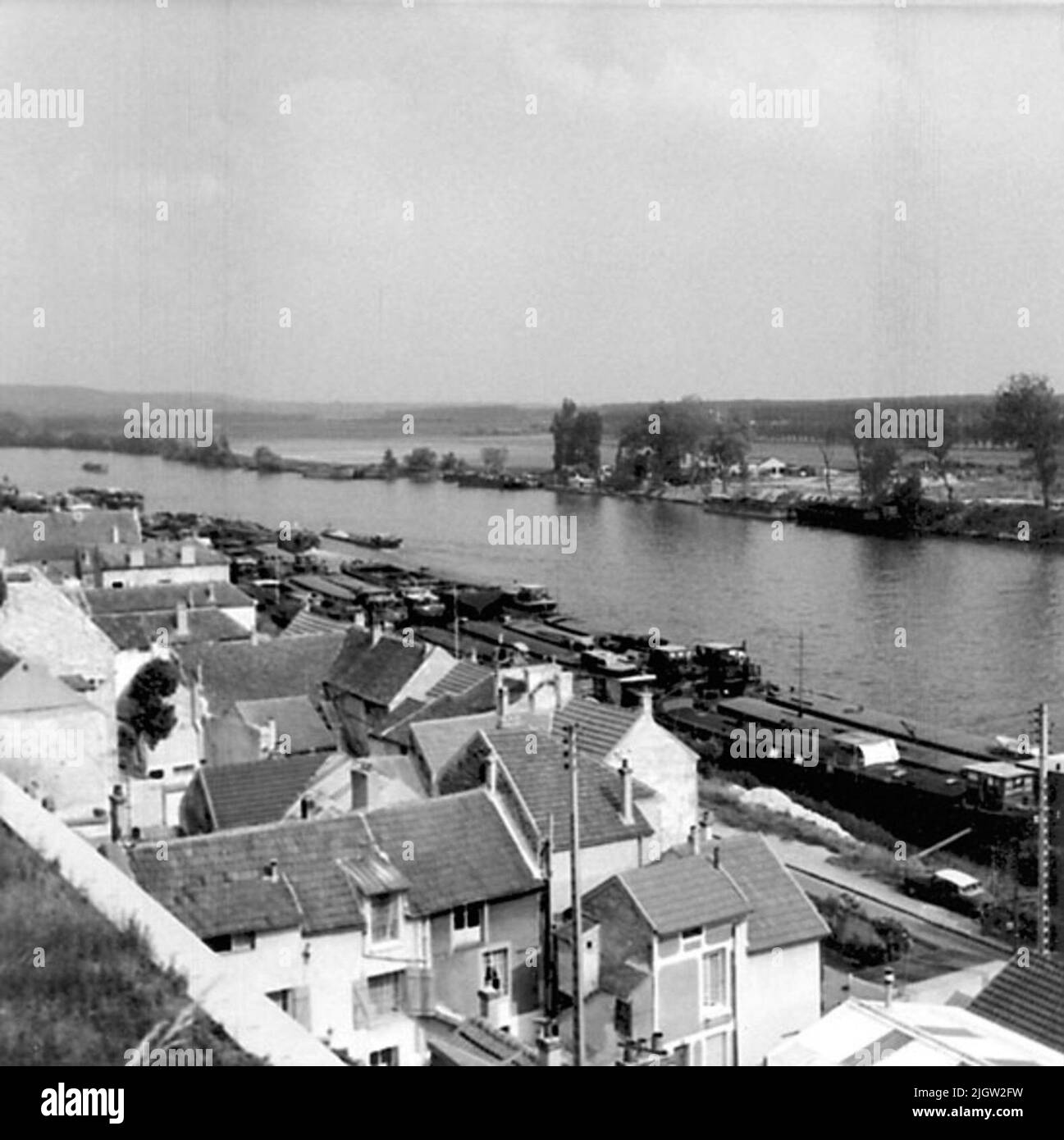 Vista di una piccola città su un fiume con botti di fiume ecc Foto Stock