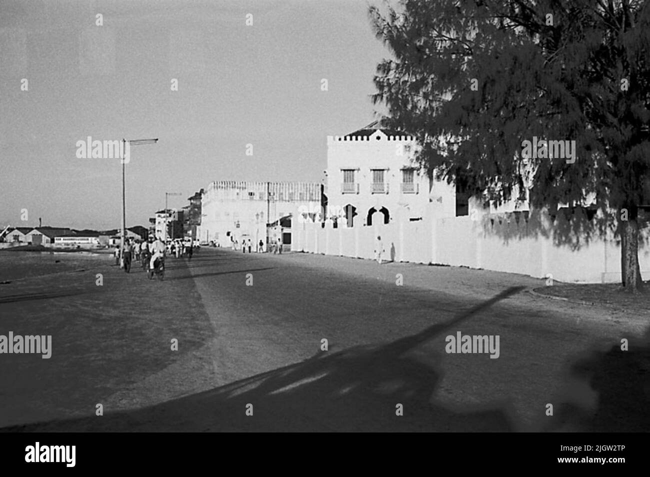 African journey, zanzibars acquisizione semplice: Libri e materiale di archivio.35 immagini in serie. La foto è stata scattata intorno al 1961-09-12. A sinistra si trova una baia sul mare, a destra si trovano alcuni edifici residenziali. Al centro va una strada. Alcuni uomini e donne camminano sulla strada. Foto Stock
