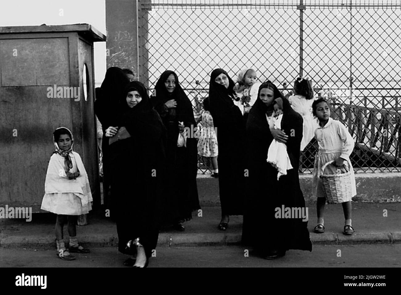 La foto è stata scattata intorno al 1961-09-20. Un paio di donne e bambini si trovano in una recinzione in un porto. Le donne indossano la tappezzeria tradizionale, il vestito nero e il velo nero. Tuttavia, la faccia è visibile. African travel35 immagini in serie. Foto Stock