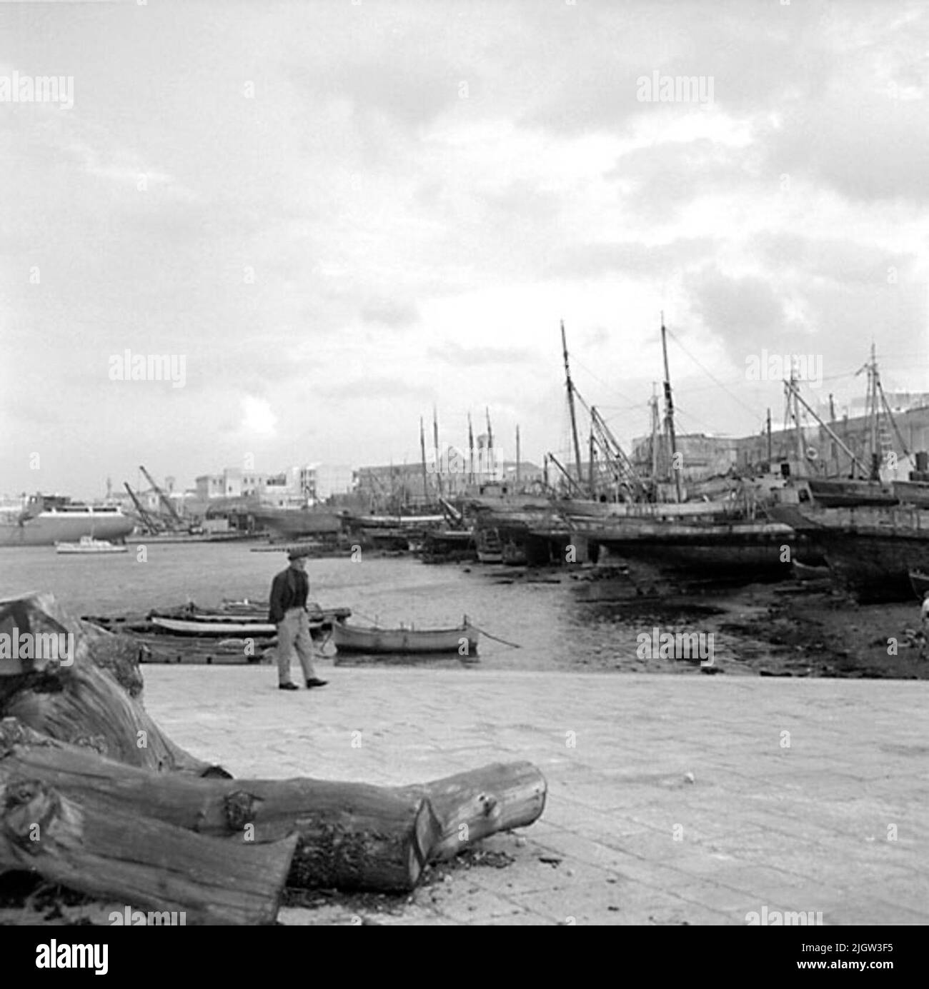 16. Italia. Il giornale fotografico è disponibile presso B.M.A. + Album fotografici. Acquisizione: Libri e materiale di archivio. Foto scattate 1959-10-28,12 Foto in serie. Secondo le note: Italia. Costa Adriatica, molfetta, 28/10-59. Una serie di immagini dalla stessa barca di legno girare come le ultime immagini su Film 15. TotalVy dei letti STAP. In un porto si trovano diverse barche. Alcune si trovano sulla spiaggia. In primo piano è un uomo sulla banchina. Sullo sfondo c'è una società. Foto Stock