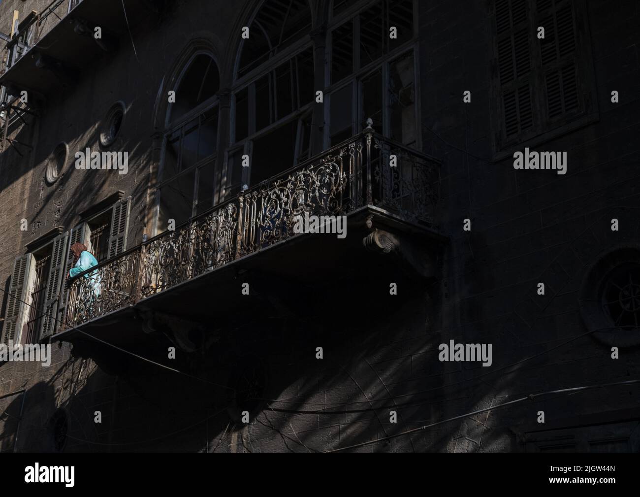 Donna in piedi sul balcone di una vecchia casa del patrimonio libanese, Beirut Governorate, Beirut, Libano Foto Stock