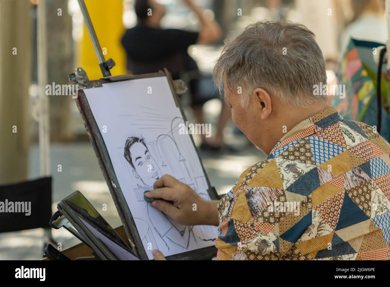 Barcellona, Spagna - 26 maggio 2022: artista di strada che dipinge un disegno su un cartone nelle ramblas di Barcellona (Spagna), fuoco selettivo sul pittore Foto Stock
