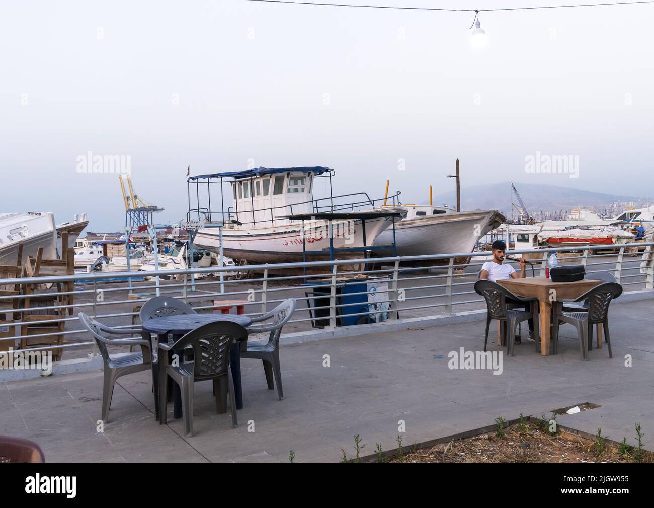 Uomo che fuma narghilè lungo il porto, Governatorato del Nord, Tripoli, Libano Foto Stock