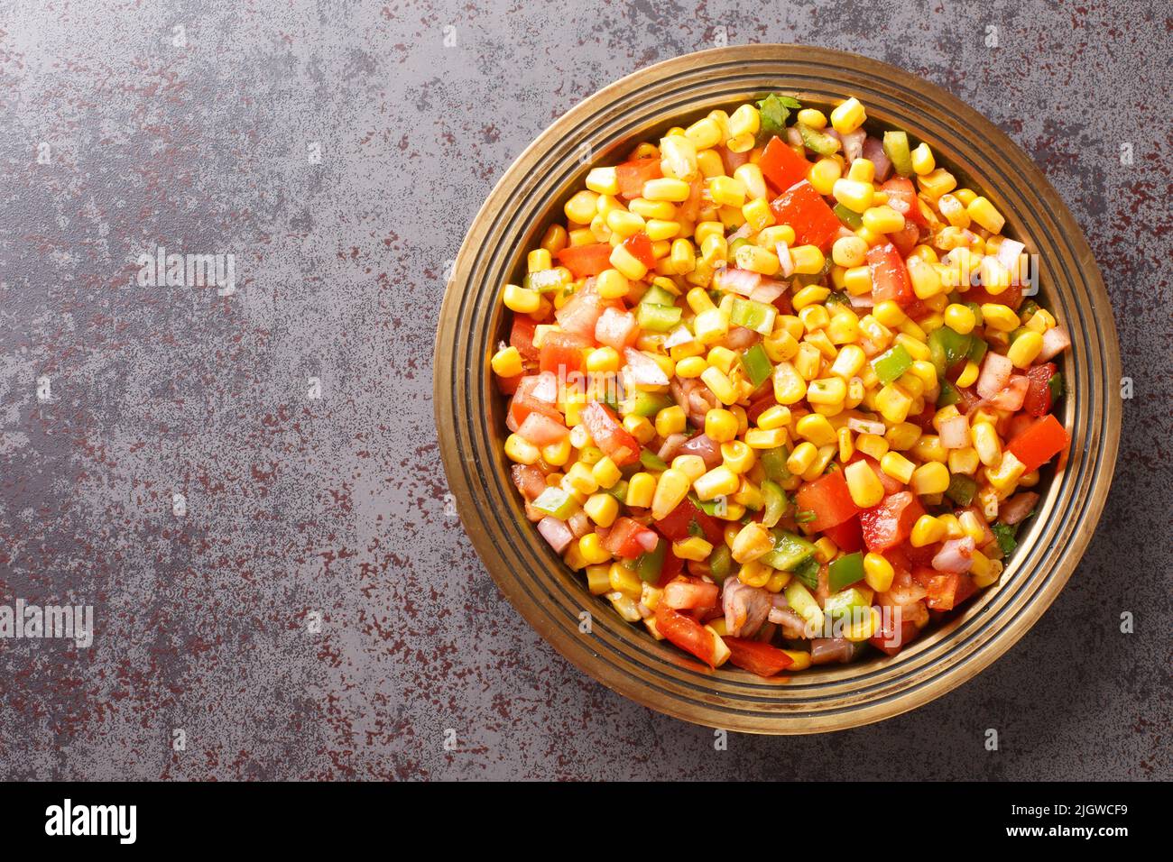 Il mais chaat è uno spuntino super veloce preparato con mais bollito, chaat masala, polvere di spezie, cipolle e pomodori su un piatto di primo piano sul tavolo. T orizzontale Foto Stock