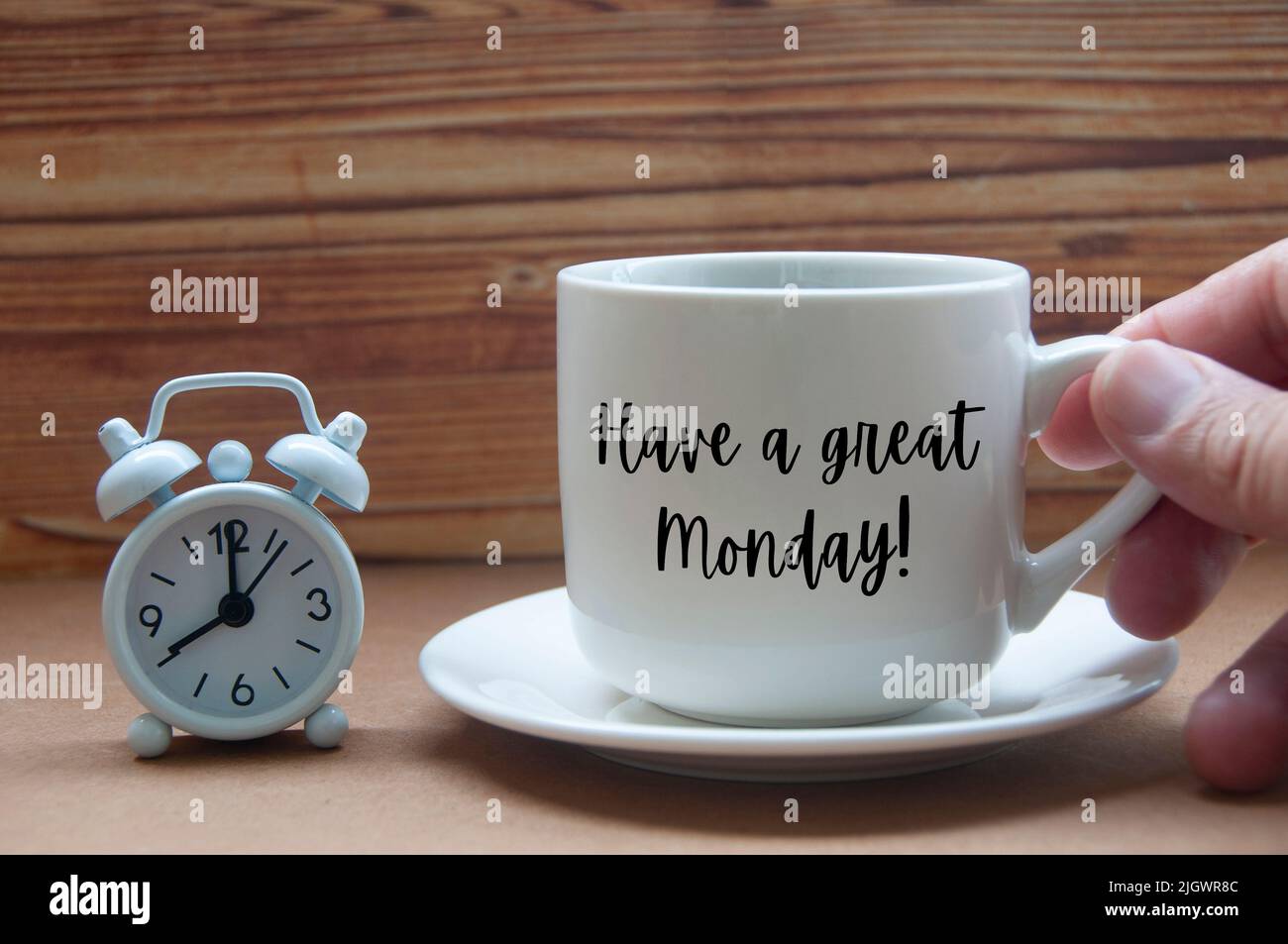Mattina saluto concetto - avere un grande Lunedi testo sulla tazza di caffè con sveglia su tavolo di legno. Concettuale Foto Stock