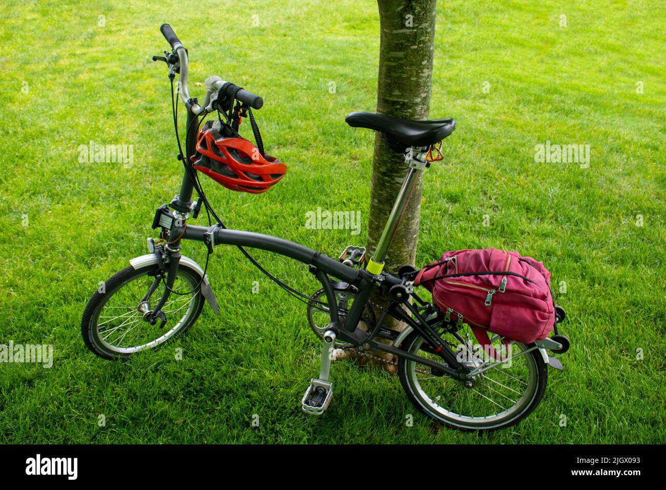 bicicletta componentistica con telaio posteriore in titanio e forcella leggera pieghevole appoggiata su un albero con casco e zaino Foto Stock