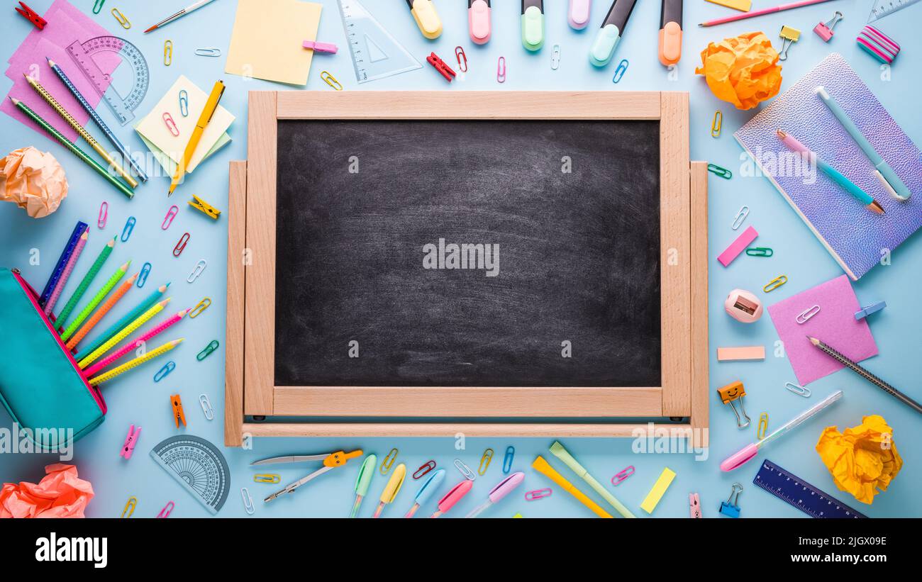 Cancelleria scolastica e blackbord su sfondo blu. Foto creativa di ritorno a scuola Foto Stock