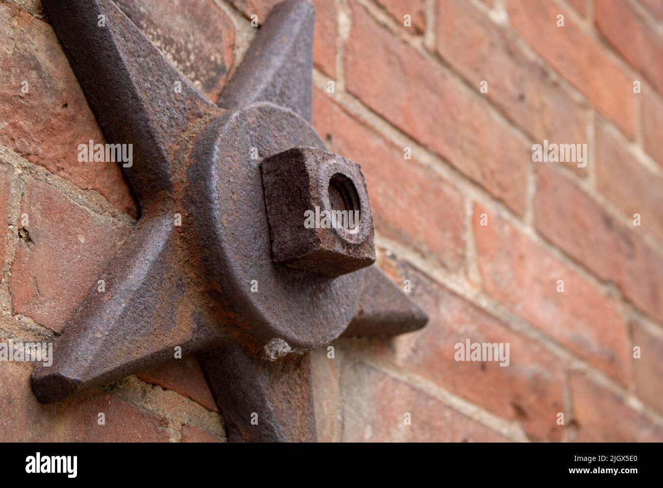 stelle decorative e strutturali in metallo imbullonate su un vecchio edificio in mattoni che sorrega il muro Foto Stock
