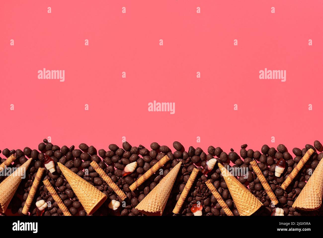 Draga di cioccolato e focaccine poste in un affascinante ordine su sfondo corallo, vista dall'alto Foto Stock Draga di cioccolato e focaccine poste in un affascinante ordine su sfondo corallo, vista dall'alto Foto Stock