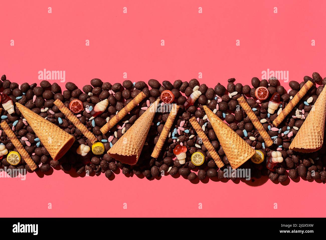 Draga di cioccolato e focaccine poste in un affascinante ordine su sfondo corallo, vista dall'alto Foto Stock Draga di cioccolato e focaccine poste in un affascinante ordine su sfondo corallo, vista dall'alto Foto Stock