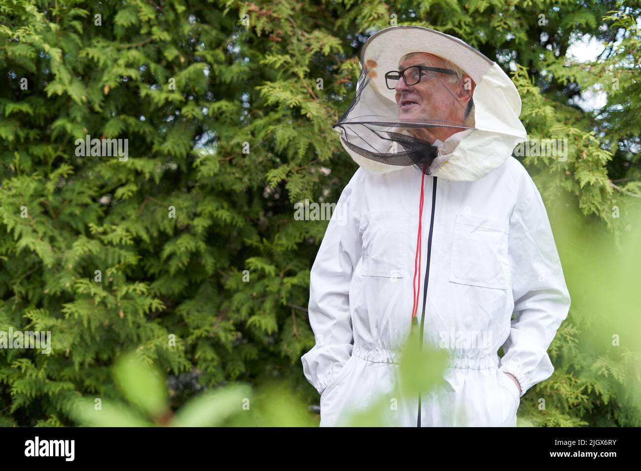 Un apicoltore rilassato che guarda da parte distratto in una fattoria Foto Stock