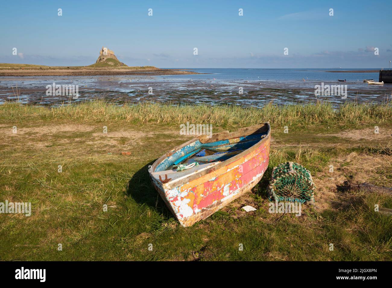 Vecchia barca di legno sulla riva con il castello di Lindisfarne a bassa marea, Holy Island, Northumberland, Inghilterra, Regno Unito, Europa Foto Stock