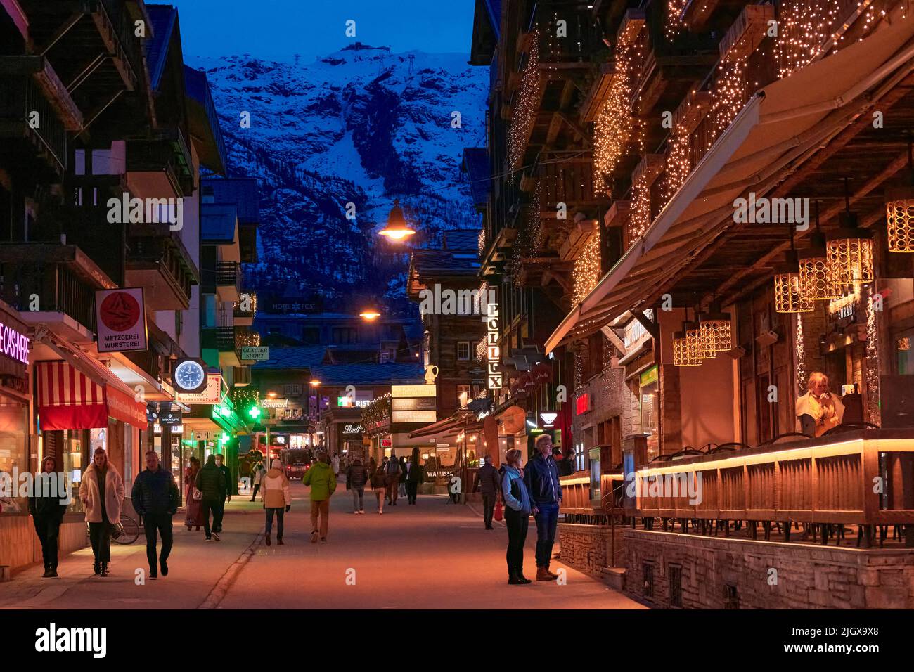 ZERMATT, SVIZZERA - Apr 11, 2022: Turisti che camminano e visitano una strada nella città di Zermatt al tramonto. Foto Stock