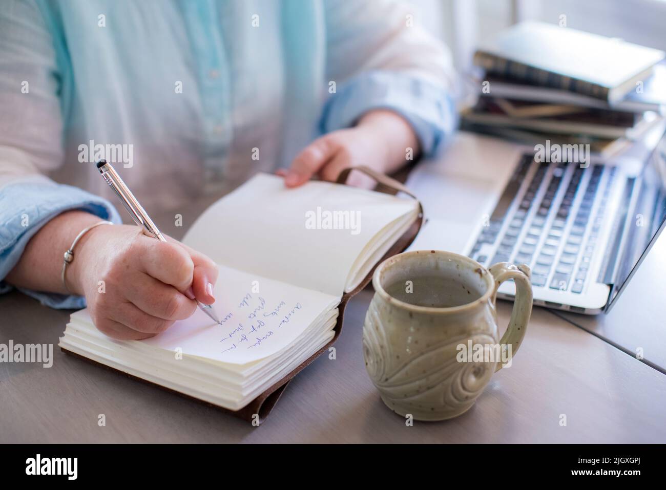 Primo piano delle mani bianche della donna che scrivono in un giornale Foto Stock