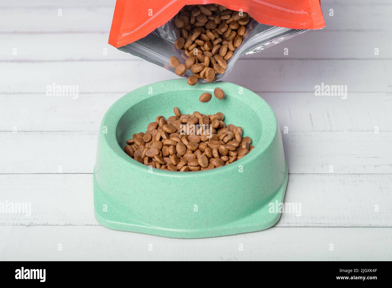 Versare gli alimenti per animali domestici in una ciotola sul pavimento. Primo piano. Foto Stock