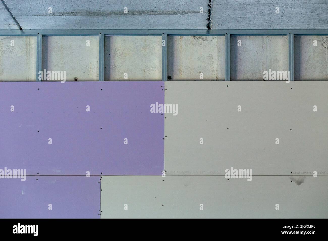 muro a secco viola e grigio installato su montanti in acciaio zincato collegati su una parete in calcestruzzo di un edificio commerciale Foto Stock