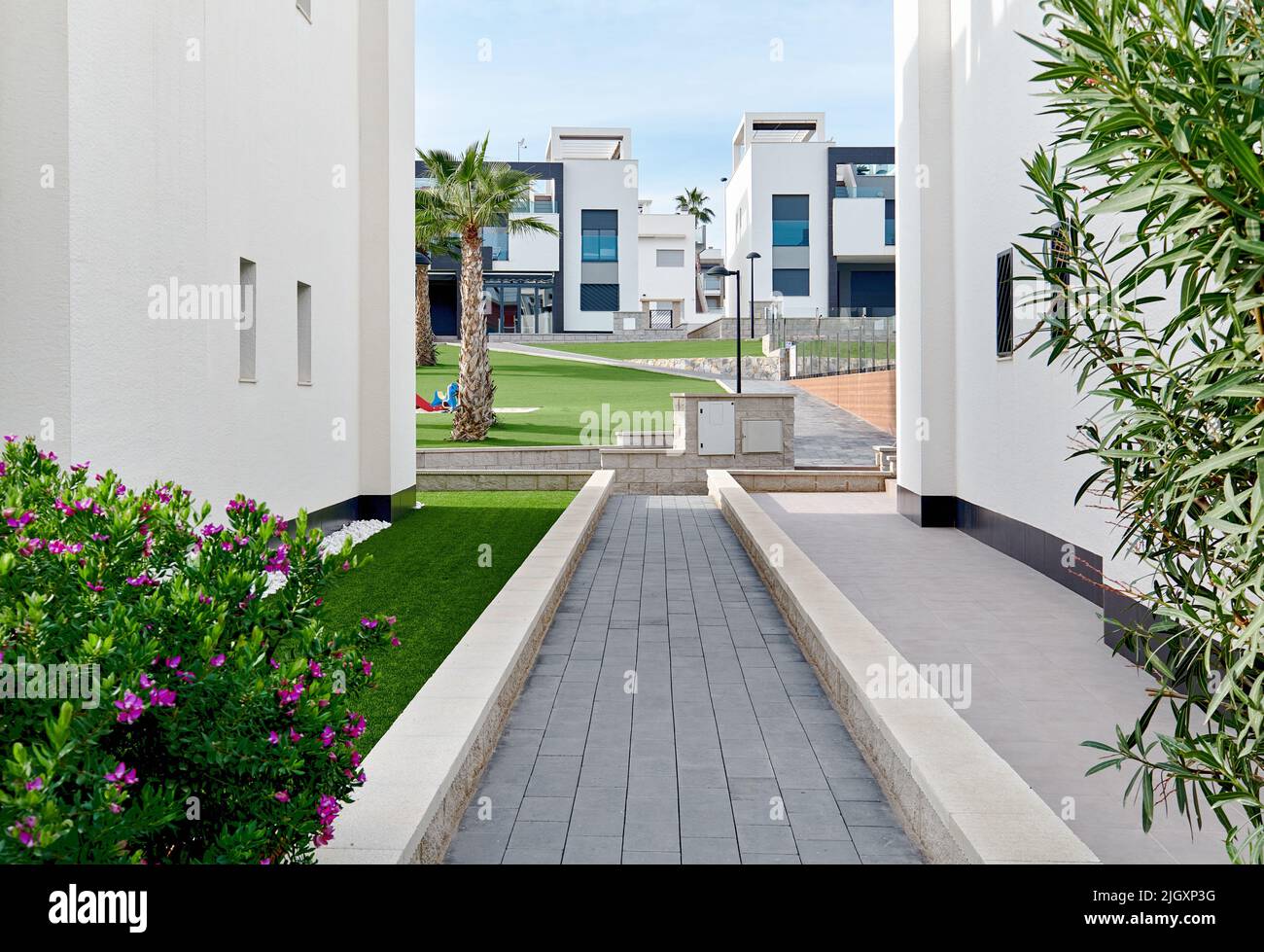 Uno stretto sentiero lungo due case bianche residenziali percorso che conduce al cortile interno di simili case cittadine Foto Stock