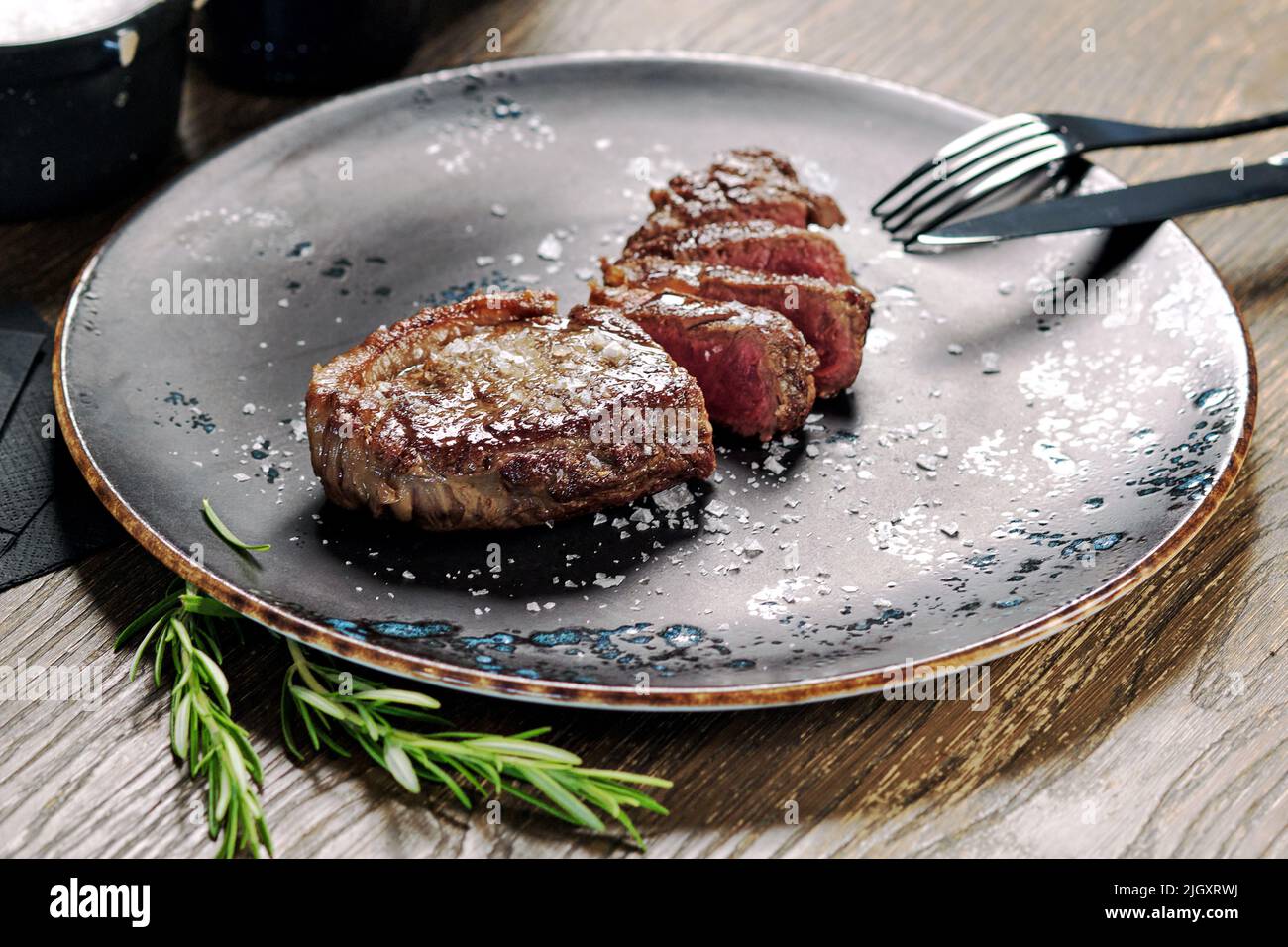 Primo piano bistecca media rara a fette servita su piatto con posate. Portata principale, piatto del ristorante, concetto di mangiare Foto Stock