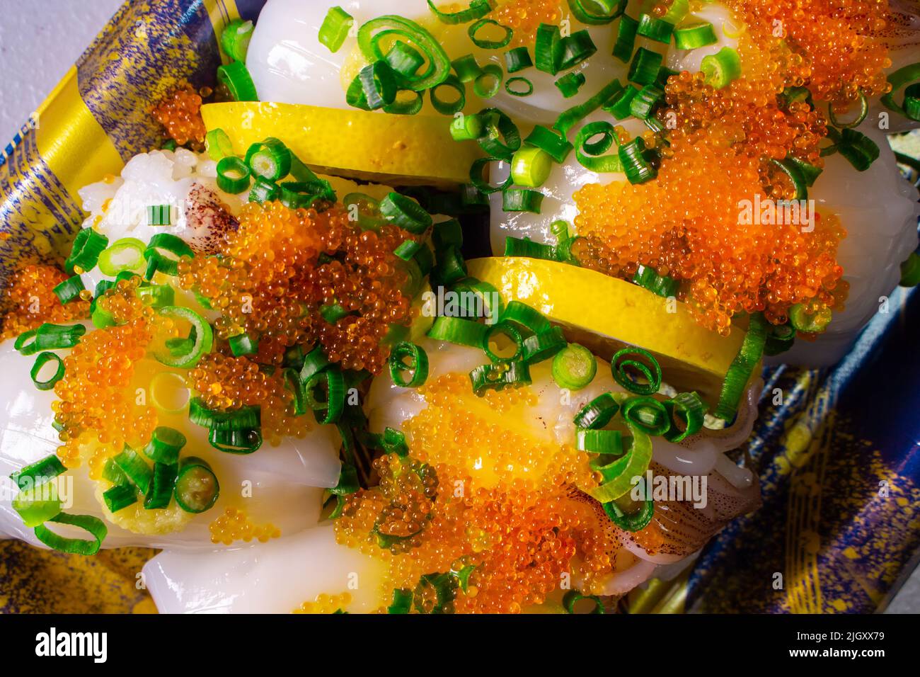 Un Ika Sushi da asporto (sushi di calamari) con Tobiko (Tobikko, uovo di pesce volante) e cipolla verde tritata in un vassoio Foto Stock