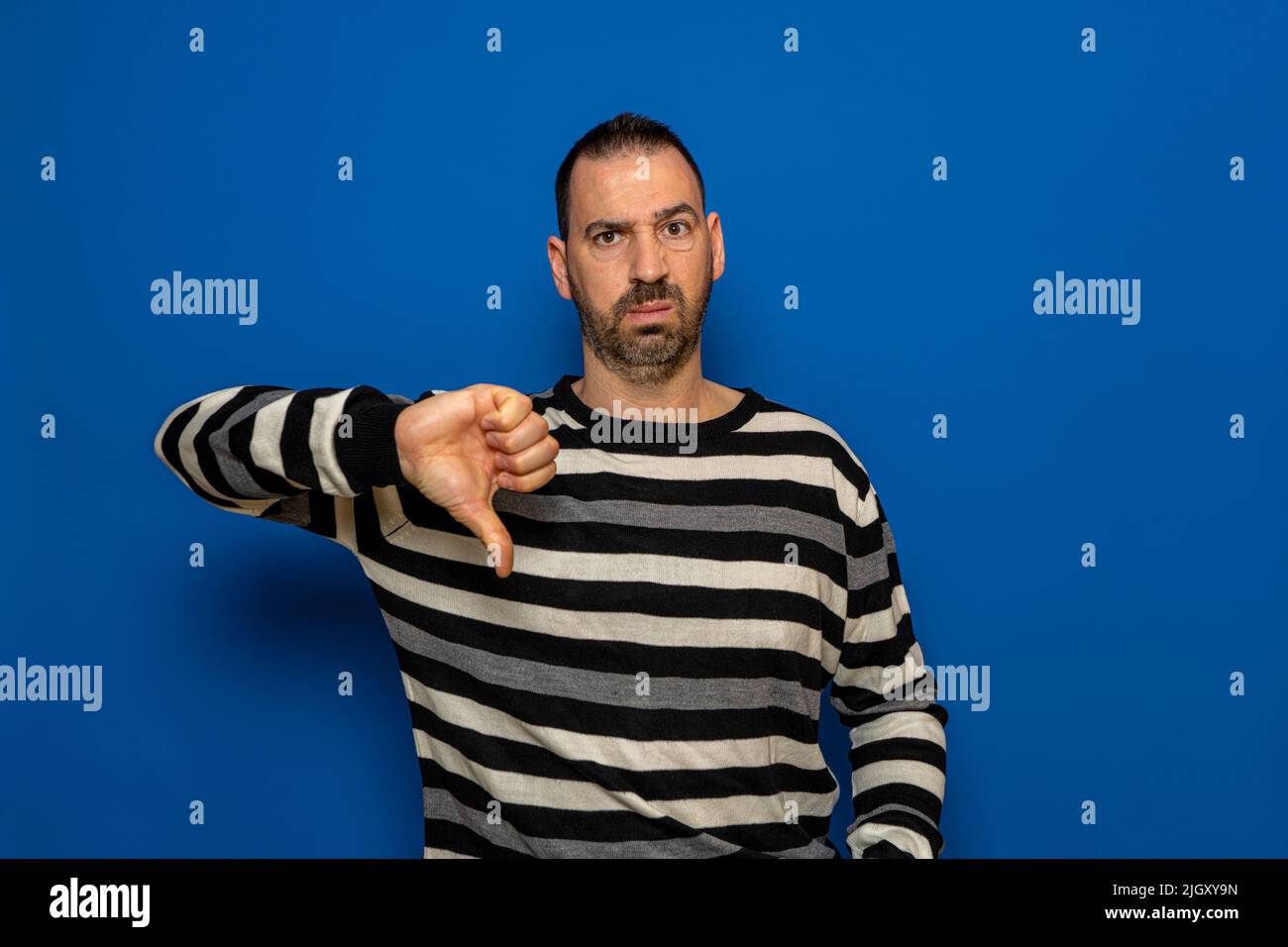 L'uomo spagnolo con barba dispiaceva posando isolato su sfondo blu parete ritratto studio. Persone Candid emozioni stile di vita concetto. Copia simulata Foto Stock