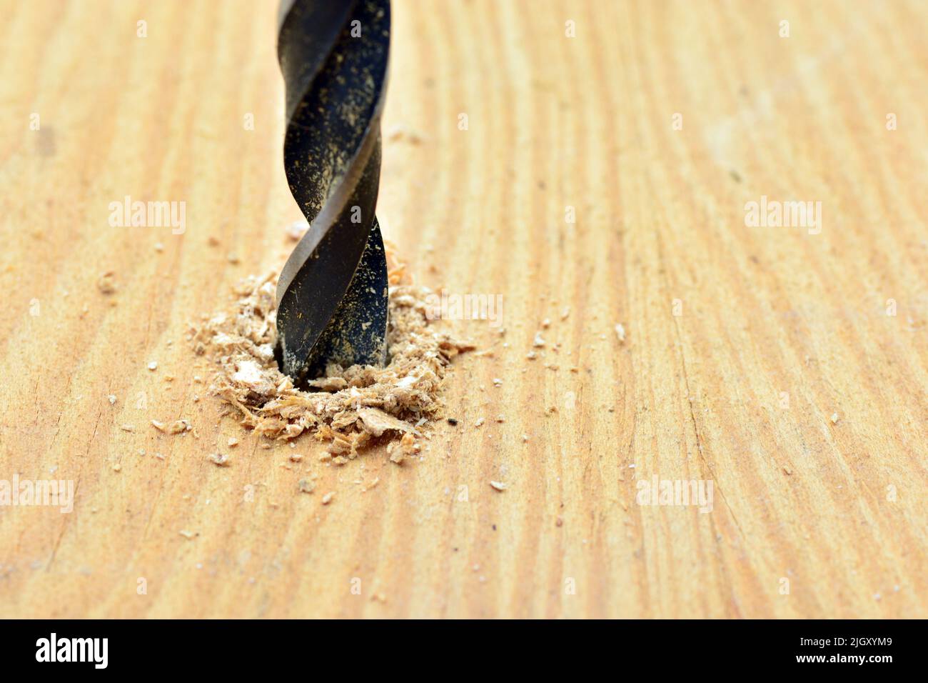 Detalle de una broca abriendo un agujero en una tabla de madera Foto Stock