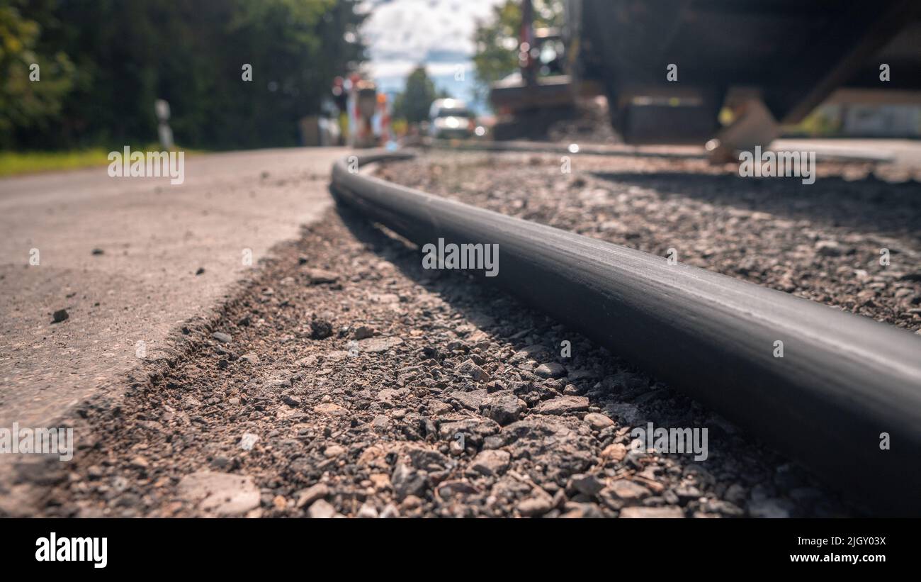Un primo piano di una pipa d'acqua nera sulla strada asfaltata in un cantiere Foto Stock