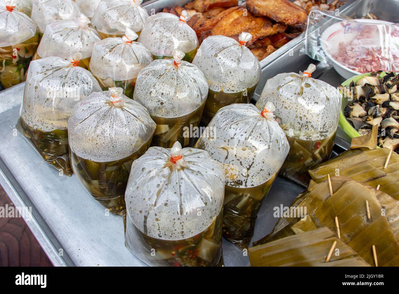L'offerta del mercato thailandese, zuppa di funghi in stile Isan in sacchetti di plastica, pesce al vapore in mousse di curry rosso avvolto in foglia e altro. Foto Stock