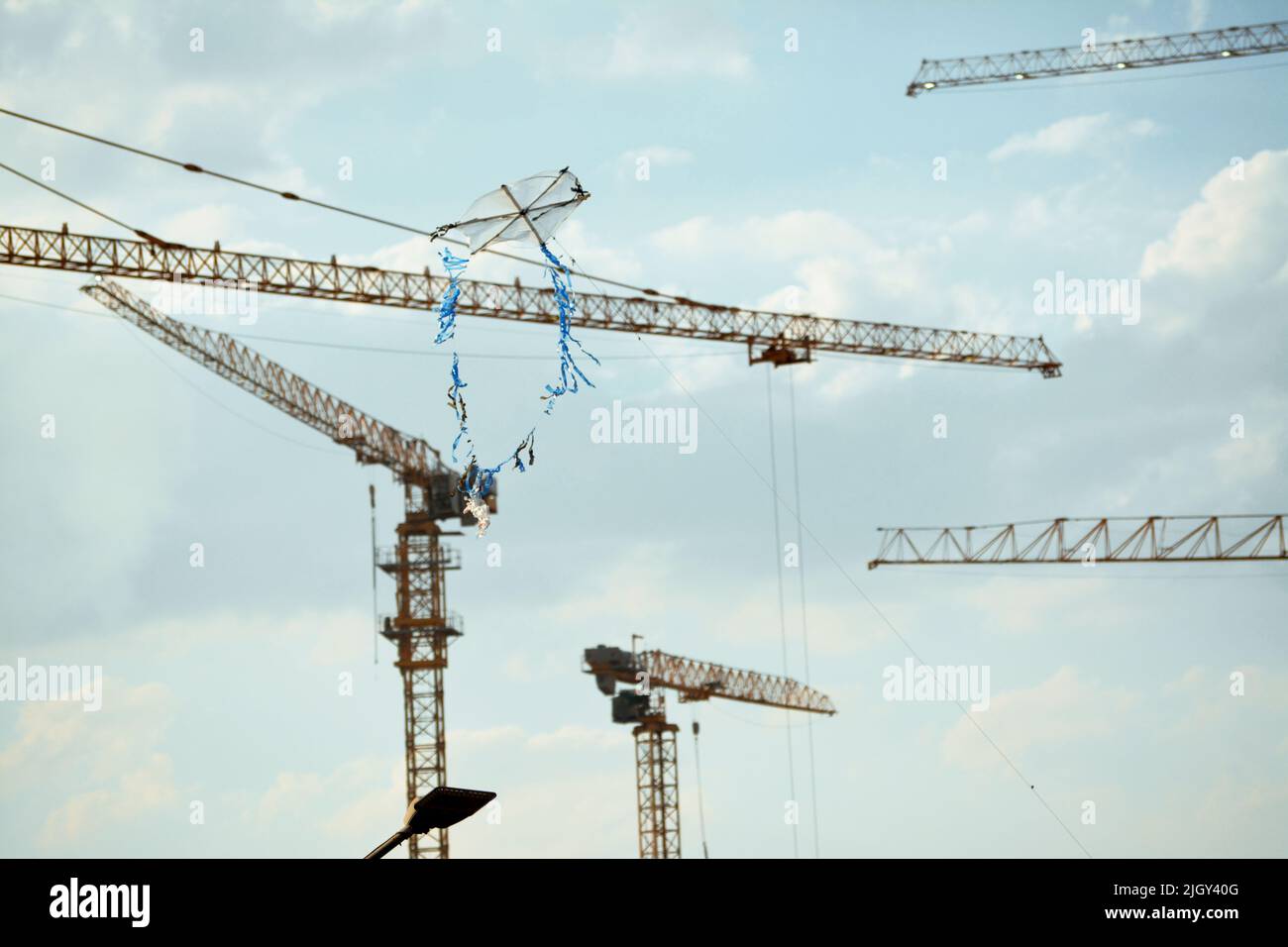 aquilone volante fatto di plastica e legno di vimini con uno sfondo di un cantiere di nuovi edifici, gru e acri di residenza di lusso Foto Stock