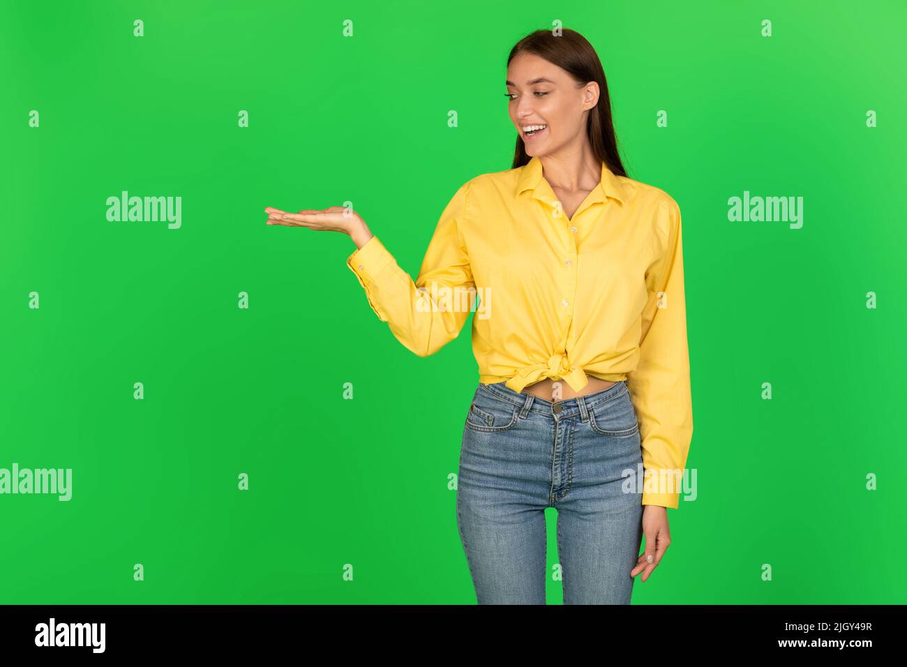 Donna allegra che tiene l'oggetto invisibile a portata di mano su sfondo verde Foto Stock