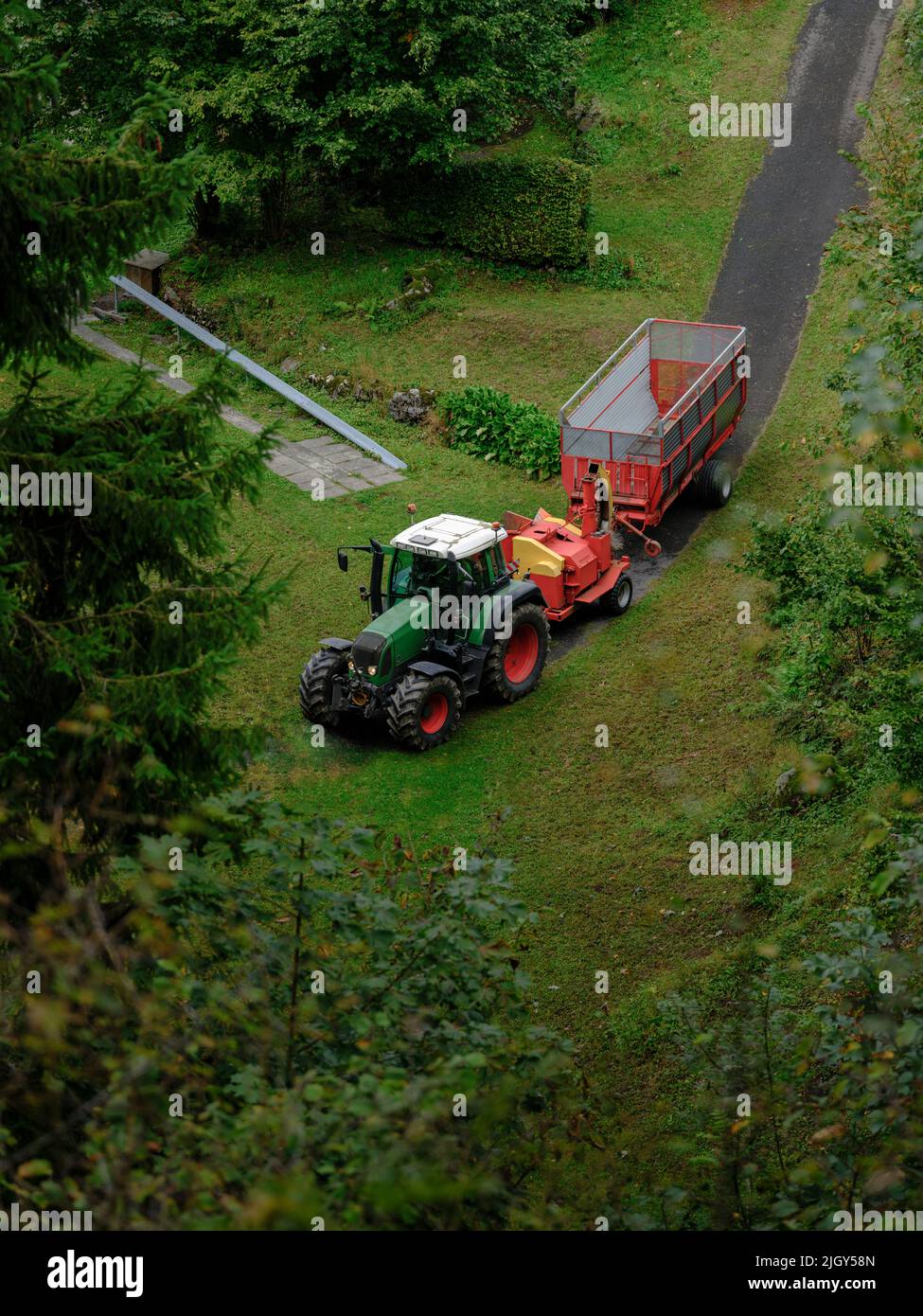 Il trattore rosso trasporta un rimorchio vuoto nel bosco. Foto Stock