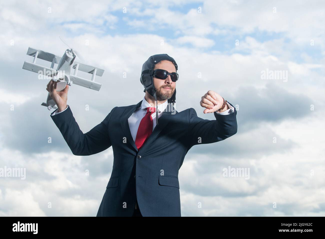 uomo d'affari in vestito e cappello pilota lancia giocattolo aereo. controllare l'orario Foto Stock