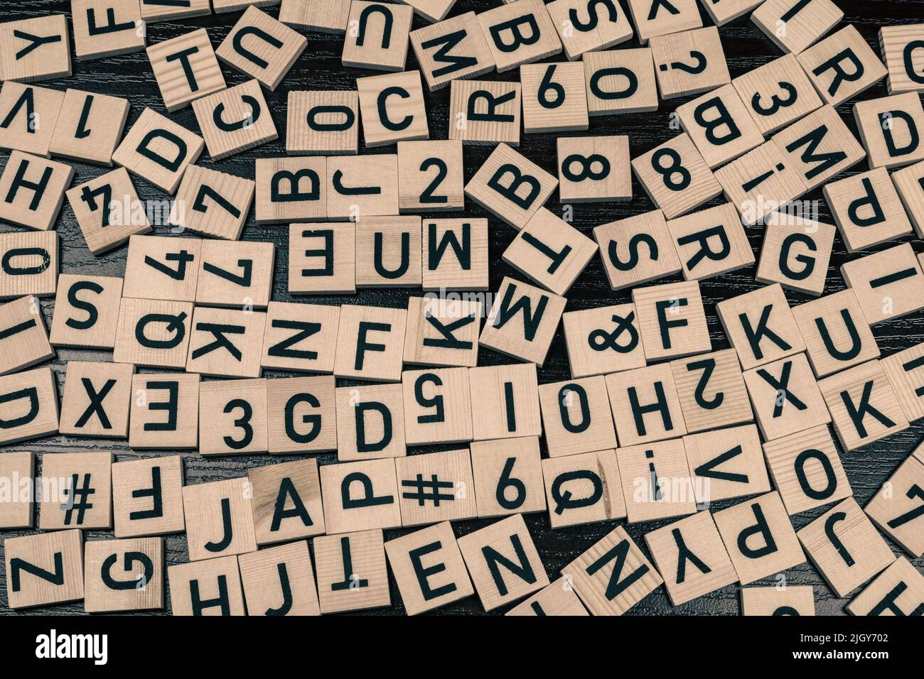 Piastrelle di legno con lettere e caratteri alfabetici latini su una tabella (sfondo nero) Foto Stock