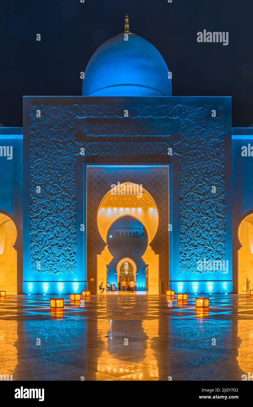 L'ingresso frontale illuminato blu della Grande Moschea Sheikh Zayed di notte Foto Stock