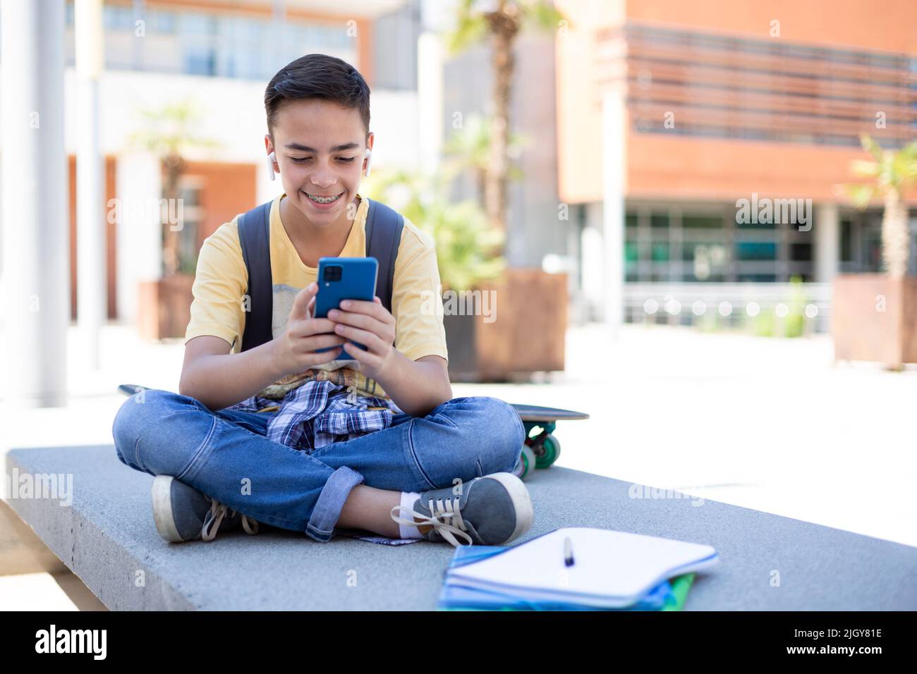 Sorridendo studente ragazzo della scuola superiore utilizzando il telefono cellulare all'aperto. Spazio per il testo. Foto Stock