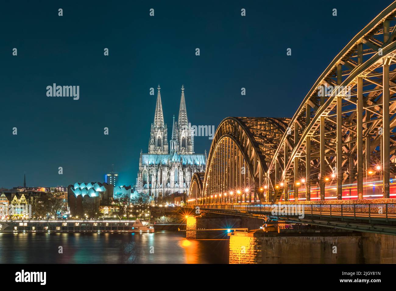 Cattedrale di Colonia illuminata e Ponte Hohenzollern di notte Foto Stock