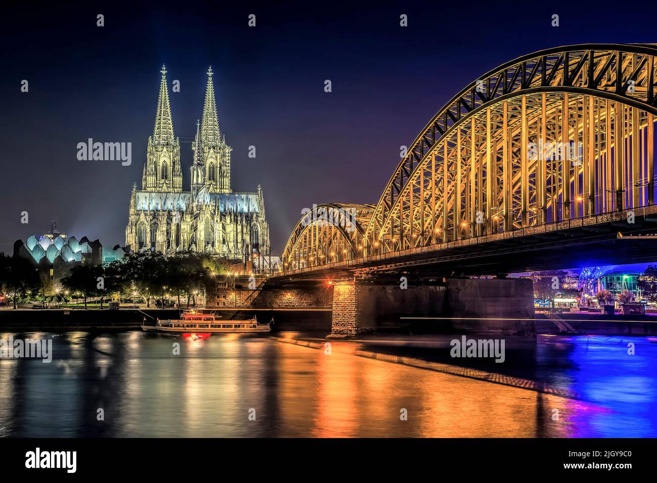 Cattedrale di Colonia illuminata e Ponte Hohenzollern di notte Foto Stock