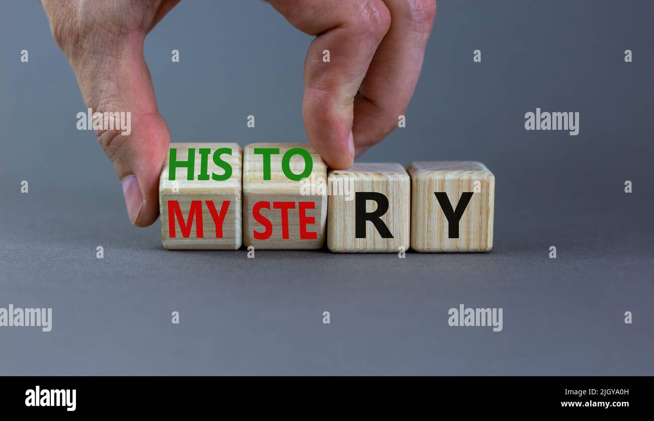 Storia contro mistero simbolo. Concetto parole Storia e mistero su cubi di legno. Mano dell'uomo d'affari. Bello sfondo grigio tavolo. Affari, Ciao Foto Stock