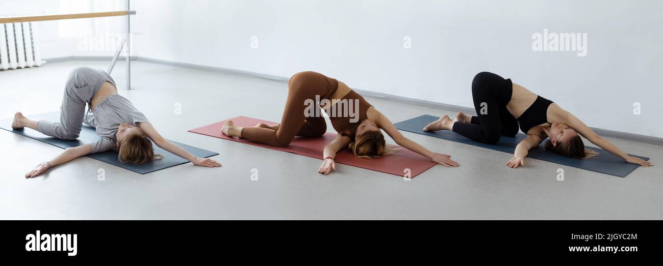 Gruppo di giovani sportivi che praticano lezioni di yoga con istruttore, stretching in Child Exercise, Balasana pose, allenarsi, close up al coperto Foto Stock