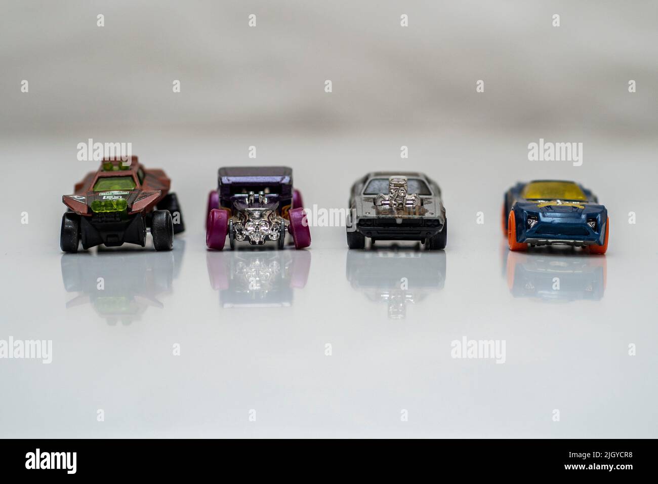 Quattro Hot Wheels in miniatura pressofuso su una superficie bianca Foto Stock