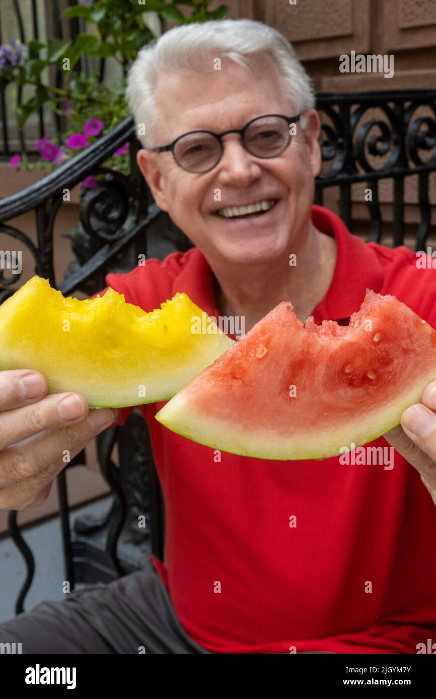 Senior Man godendo di Yellow Watermelon su un ponte stoop di New York, 2022, USA Foto Stock