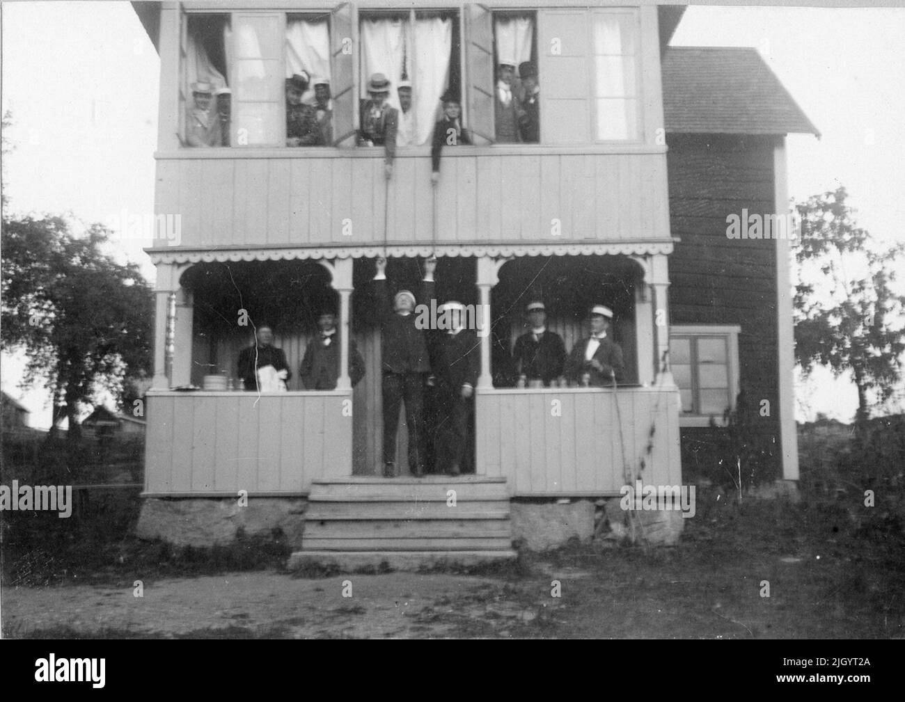 Donne e uomini, probabilmente Harald Falk all'estrema destra del portico, a Grindstugan, Uppsala, intorno al 1900. La foto è inclusa in una raccolta di foto donate da Kerstin Hallström, Uppsala, 8 novembre 1976. Queste immagini sono legate al tempo studentesco di Padre Harald Falk (1895-1905) a Uppsala. Harald Falk visse nella casa studentesca di Norrbyska a Uppsala, appartenne alla nazione Västmanland-Dala, e divenne poi sacerdote a Åtvidaberg, Östergötland e Stora Tuna, Dalarna. Nel 1919 morì nella malattia spagnola. 1895 - 1905 evento storico, Nome relativo a Objek: Falk, Harald Foto Stock