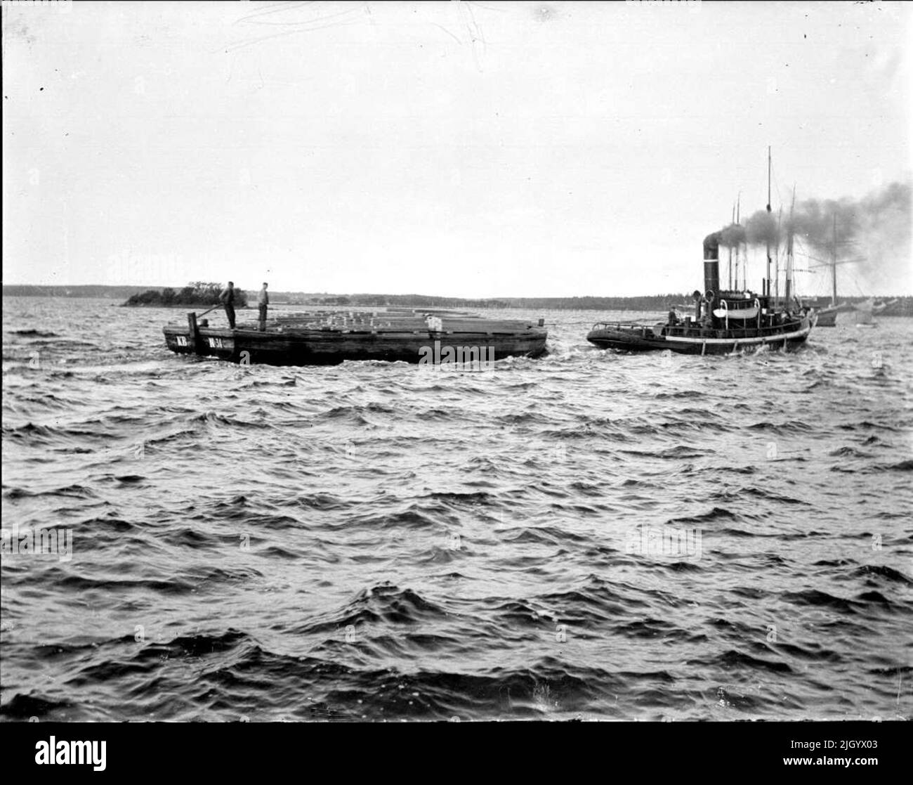 Tugboat Korsnäs i e la chiatta KB No. 31 con legname fuori Gävle. Carico della tavola sul salvataggio fuori Gävle. Il rimorchiatore è chiamato Korsnäs 1 e la chiatta KB n. 31. Informazioni fornite da Torbjörn Norman, Björklinge. Foto Stock