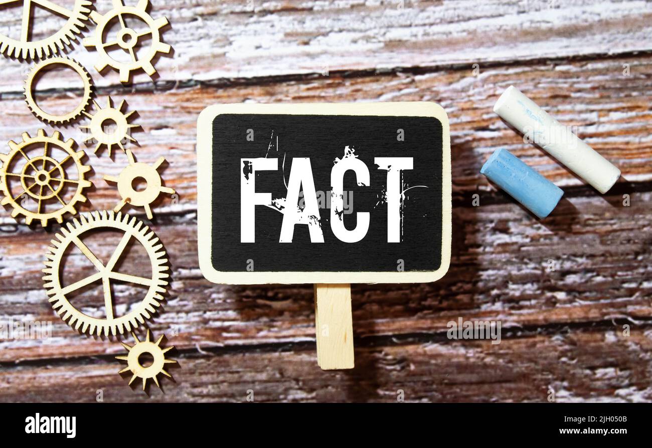 Fatto - parola attraverso lente di ingrandimento su sfondo giallo. Foto Stock