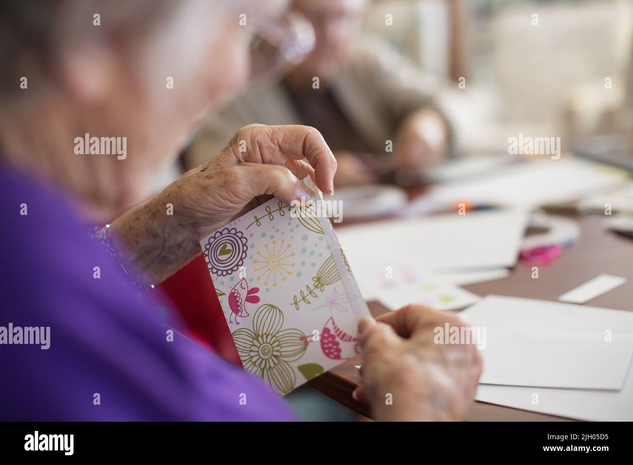 PRIMO PIANO DI UNA SIGNORA ANZIANA IN UNA CURA ANZIANA CASA FACENDO LA CARTA FARE Foto Stock