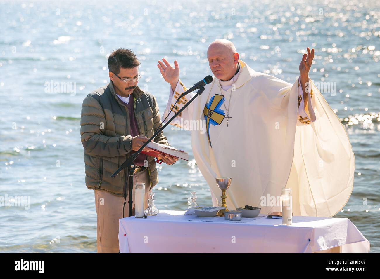 Il vescovo cattolico romano Mark Hagemoen con l'uomo indigeno di Dene benedice il grande lago dell'orso nella Comunità di Deline, territori nordoccidentali, Canada Foto Stock