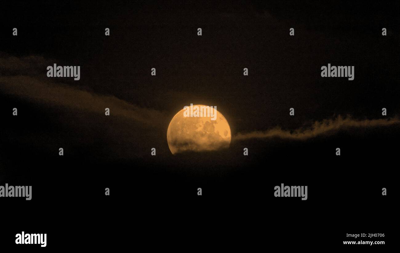 Glasgow, Scozia, Regno Unito luglio 13th 2022. UK Meteo: Super Buck Moon lotta attraverso un cielo nuvoloso sopra le luci del sud della città dopo una giornata mutevole che pioveva. Credit Gerard Ferry/Alamy Live News Foto Stock