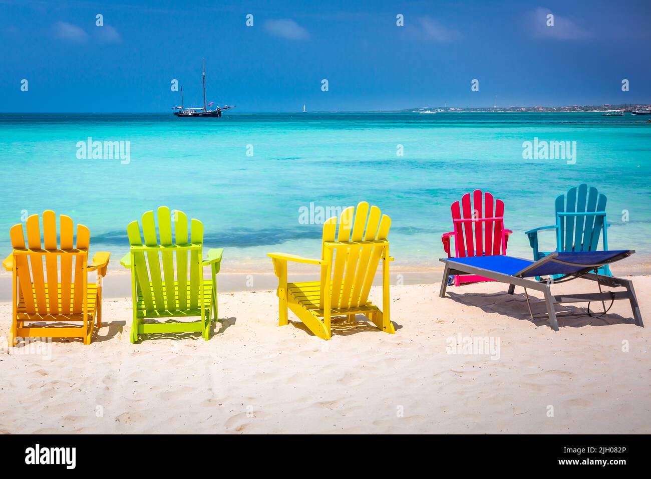 Sedie colorate sulla spiaggia di palme ad Aruba con caravel nave, Caraibi Foto Stock