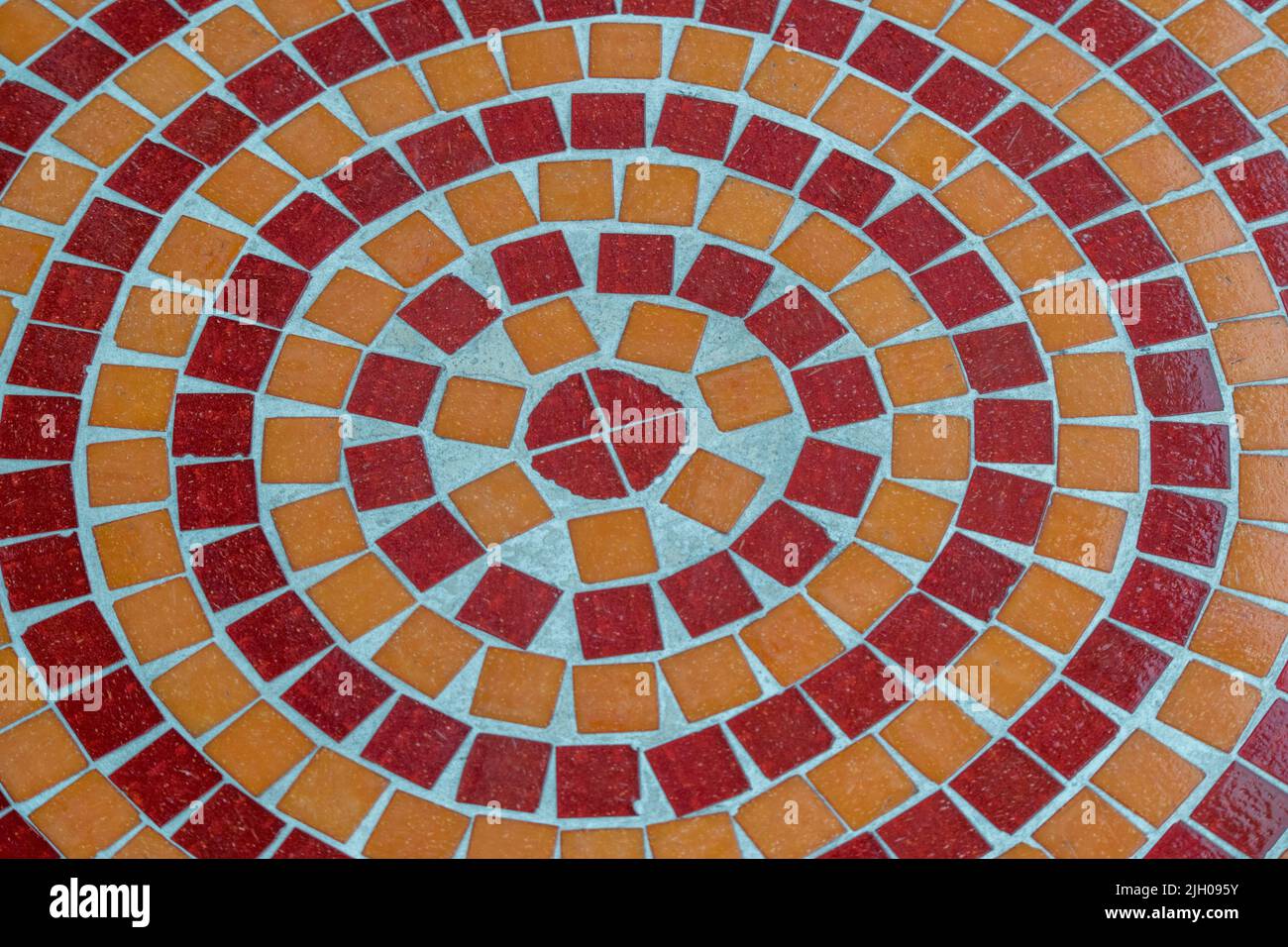 Piano portapaziente con motivo a mosaico rosso e arancione rotondo Foto Stock