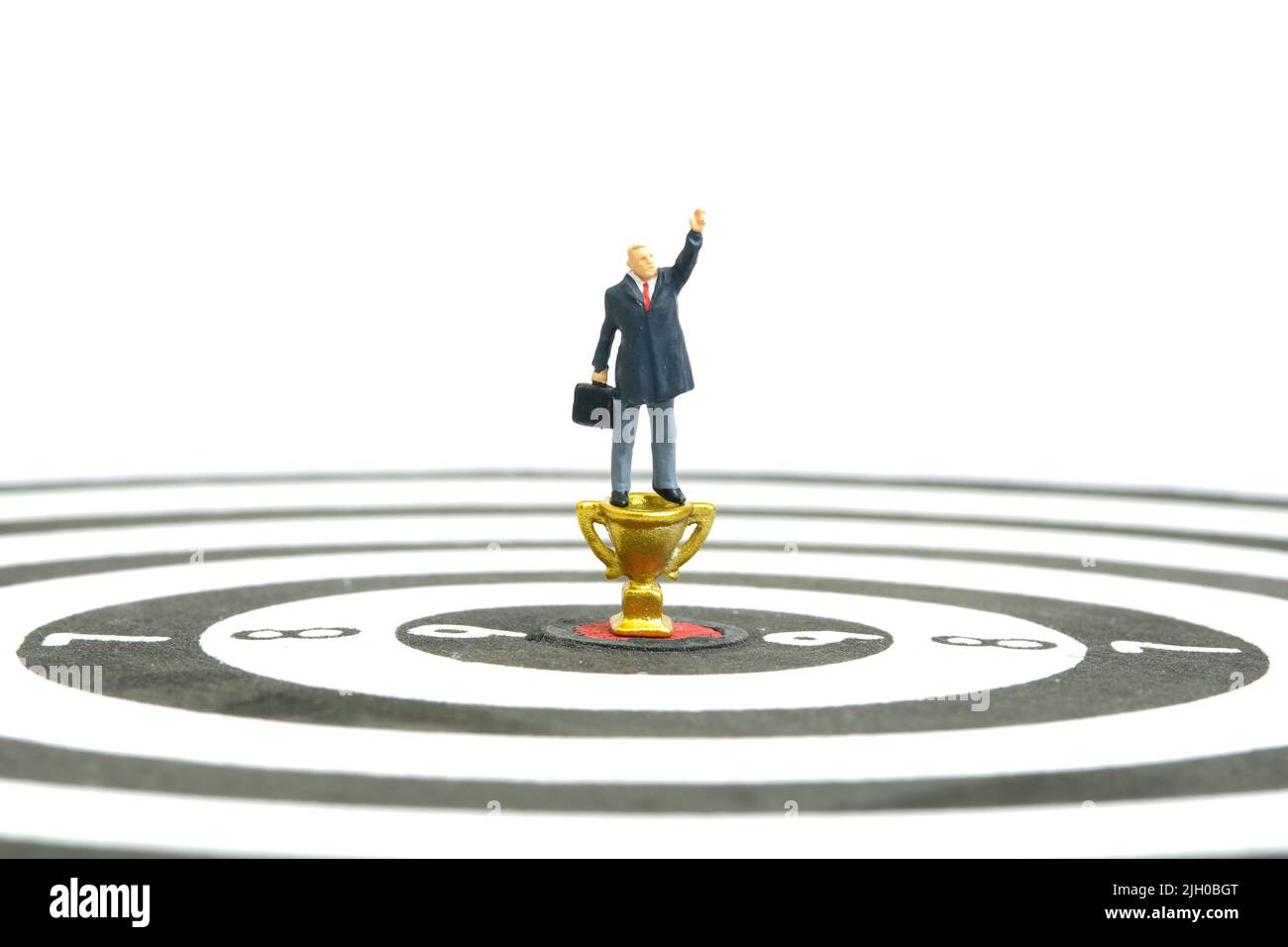 Fotografia di personaggi giocattolo in miniatura. Un uomo d'affari determinato che punta al trofeo d'oro per vincere o diventare un vincitore. Isolato su sfondo bianco. Immagine Foto Stock